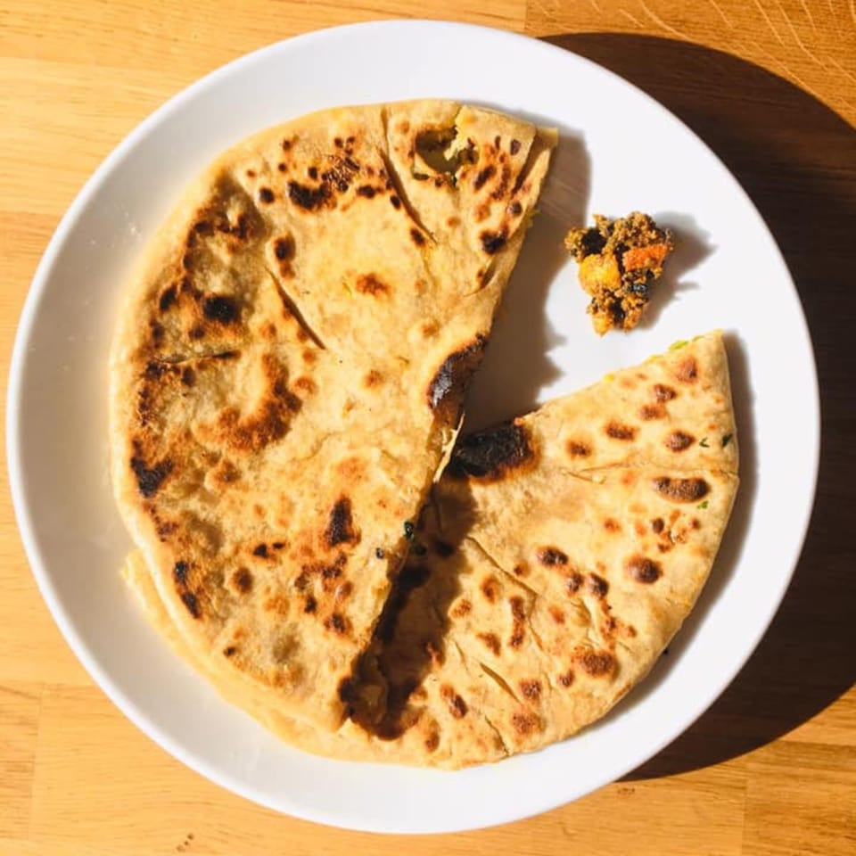 Two pieces of golden-brown flatbread, one with a bite taken, and a small pile of relish on a white plate.